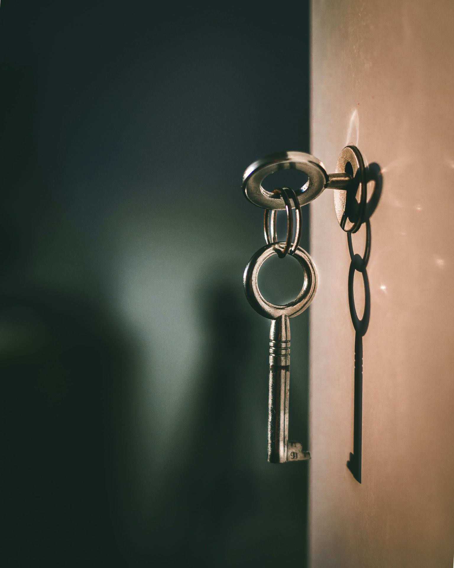 A metal key in a keyhole with a shadow on a wall
